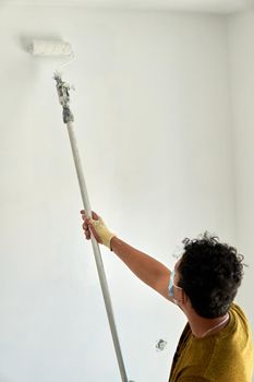 Painter painting a white room with a roller