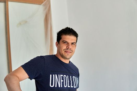 Portrait of a worker in a blue shirt while painting a room