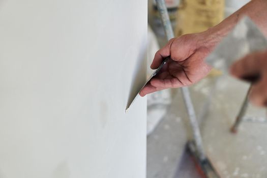 Painter working with spatulas in a room white