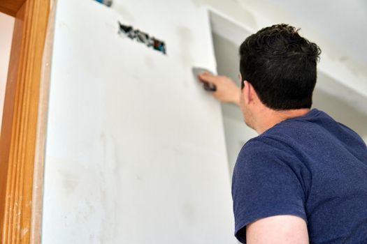 Painter working with spatulas in a room white