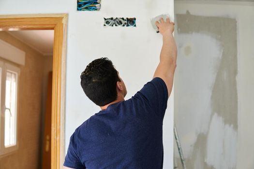 Painter working with spatulas in a room white