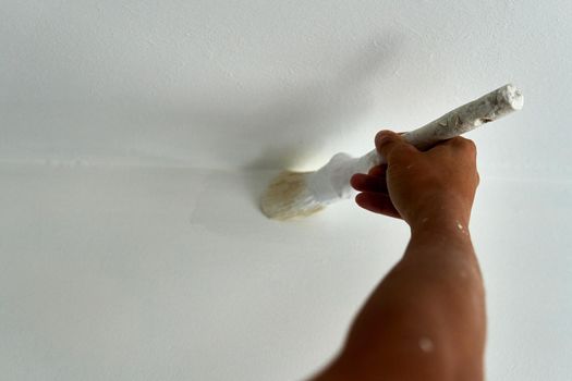 Painter painting a white room with a brush