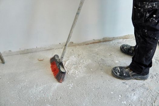 Worker sweeping up the dust of a renovation