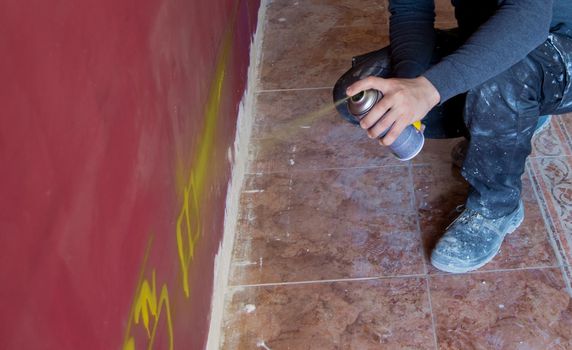 Bricklayer marking with a yellow spray on the purple wall of a house under renovation.