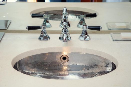 Chrome metal sink with mixers in the bathroom.