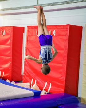 A young guy performs a jump somersault, in training. Gymnastics.