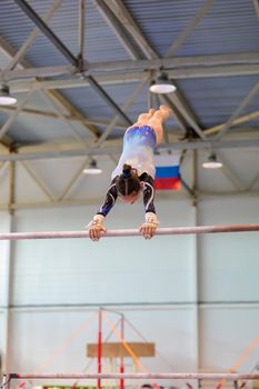 A girl in sportswear performs an exercise on the uneven bars. Rhythmic gymnastics, training in the hall. Moscow, Russia May 19, 2019