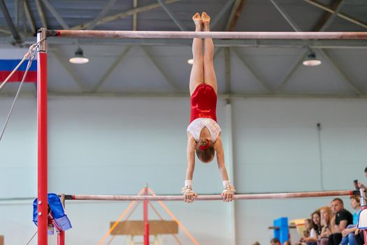 A girl in sportswear performs an exercise on the uneven bars. Rhythmic gymnastics, training in the hall. Moscow, Russia May 19, 2019
