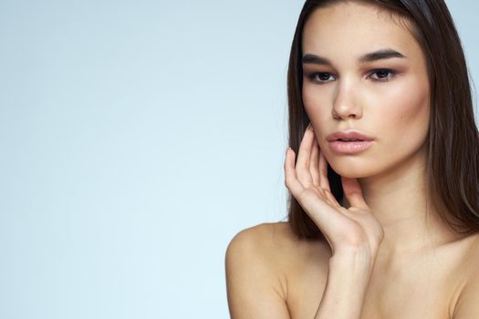 Woman with naked shoulders long hair clean skin cropped view blue background. High quality photo
