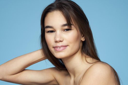 Woman with naked shoulders long hair cosmetics attractive look blue background. High quality photo