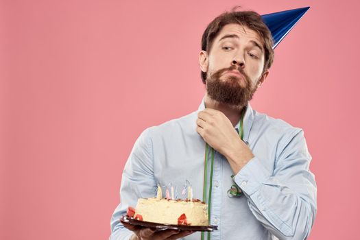 Bearded man with cake tongue on a pink background cropped view and a blue cap on his head. High quality photo