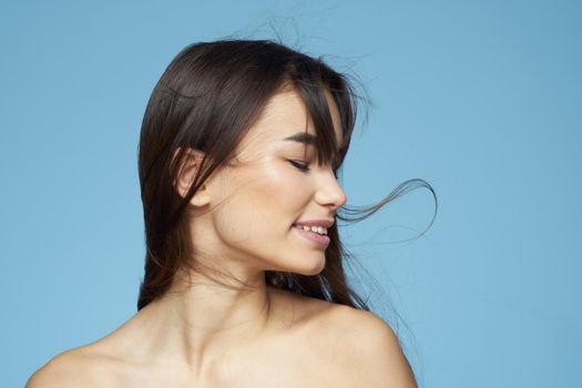 Woman with naked shoulders long hair cosmetics attractive look blue background. High quality photo