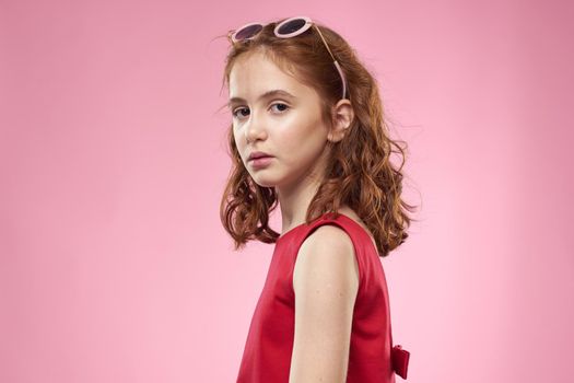 Cheerful little girl childhood dark glasses red dress lifestyle pink background. High quality photo