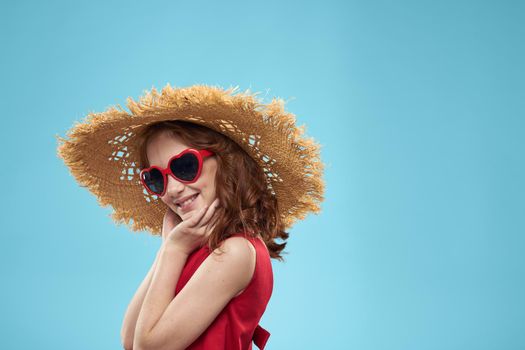 Girl in a beach Straw hat in sunglasses curly hair fun blue background. High quality photo