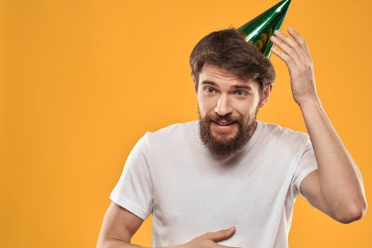 Man with cake on yellow background birthday party hat cropped view. High quality photo