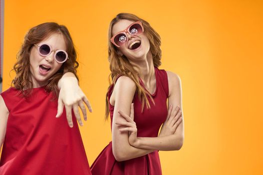 Two sisters and fun sunglasses fashion Friendship yellow background family. High quality photo