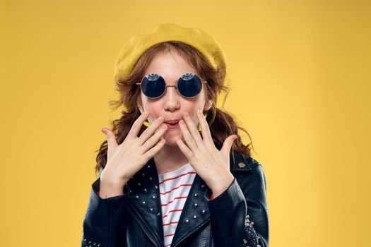 Cheerful little girl in sunglasses and hat lifestyle studio yellow background fashion. High quality photo