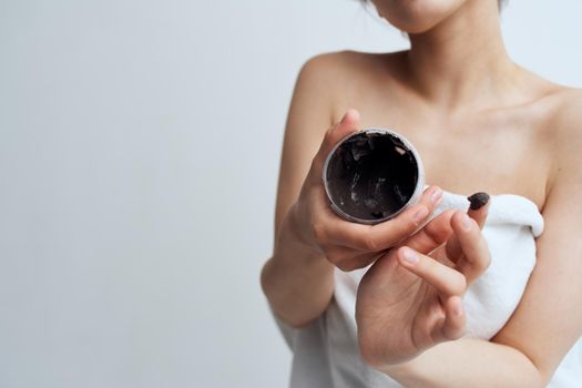 Pretty brunette naked shoulders black cream skin care care close-up. High quality photo