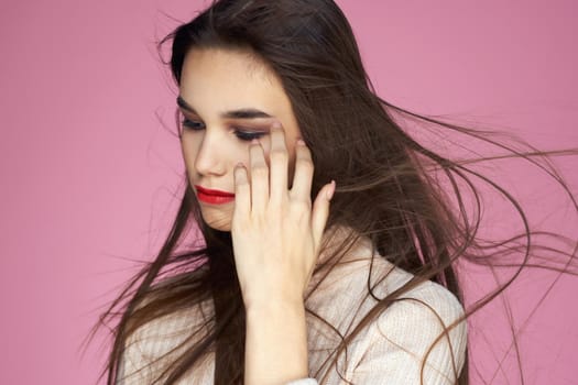 Pretty brunette in a white sweater red lips attractive look pink background. High quality photo