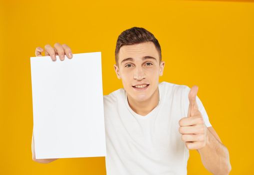 Man with a white sheet of paper on a yellow background advertising marketing manager. High quality photo