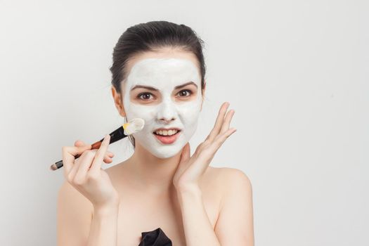 cheerful brunette naked shoulders brush in hands applying cream. High quality photo