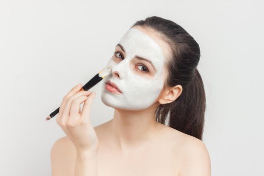 brunette with bare shoulders brush in hand skin care. High quality photo