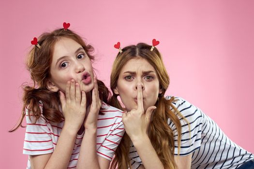 cheerful girl and woman on a pink background sisters family emotions. High quality photo
