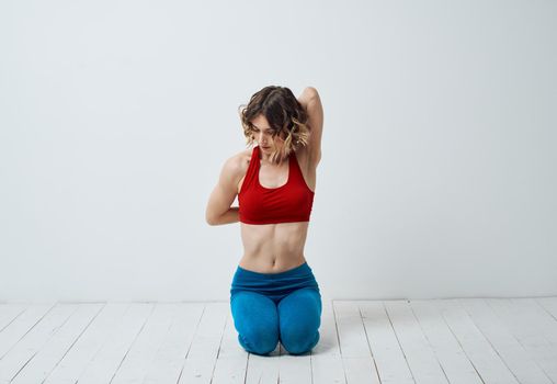 A woman in sportswear is doing yoga in a bright room and gesticulating with her hands. High quality photo