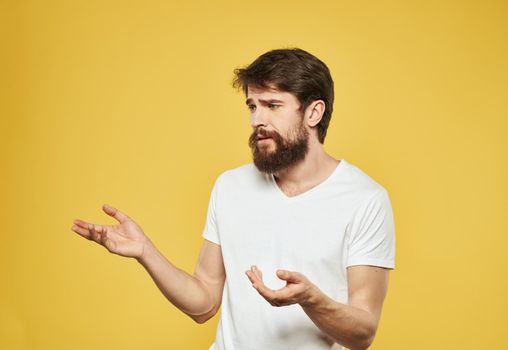 Emotional guy gesturing with his hands on a yellow background model side view. High quality photo