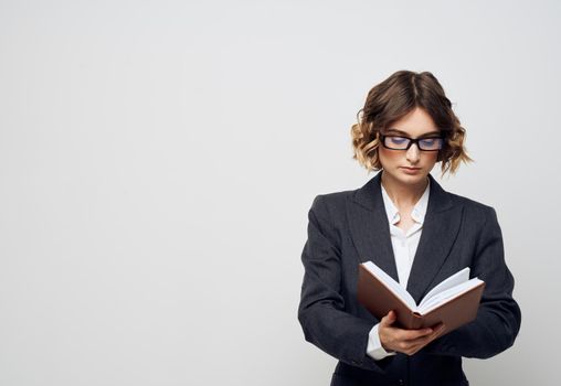 Business woman with a book in her hands on a light background classic suit fashionable hairstyle Copy Space. High quality photo