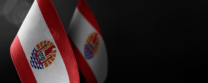 Small national flags of the French Polynesia on a dark background.