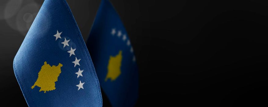 Small national flags of the Kosovo on a dark background.