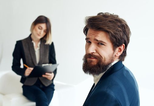 Business woman In a bright room and an upset man with a beard in the foreground is job interview. High quality photo