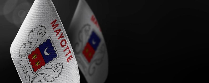 Small national flags of the Mayotte on a dark background.