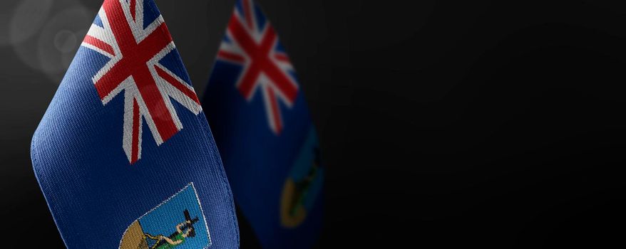 Small national flags of the Montserrat on a dark background.