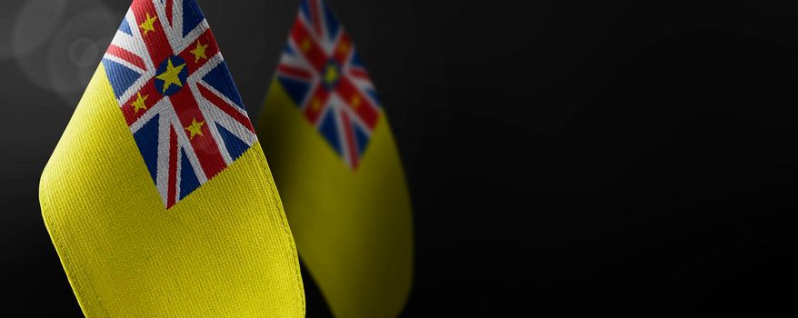 Small national flags of the Niue on a dark background.