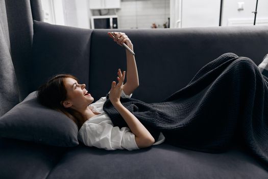 woman lies on the couch with a phone in her hand side view interior comfort. High quality photo