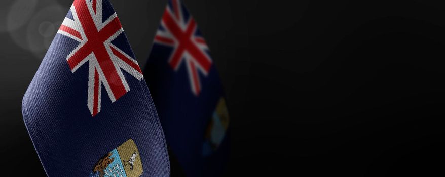 Small national flags of the Saint Helena on a dark background.