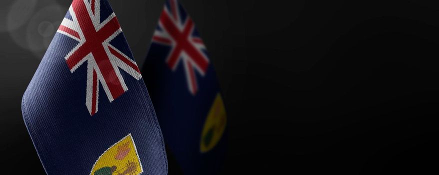 Small national flags of the Turks and Caicos Islands on a dark background.