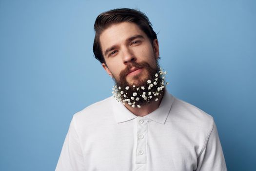 cute man flowers in beard t-shirt emotions blue background. High quality photo