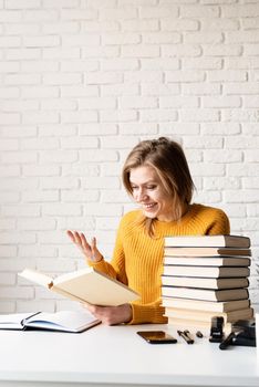 Young smiling woman in yellow sweater laughing reading a book