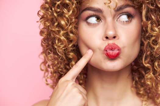 Lady curly hair red lips a look towards a grimace bright makeup close-up