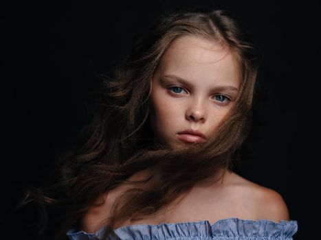fashionable girl in a sundress on a dark background curly hair blue eyes. High quality photo