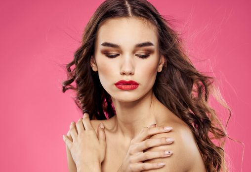 Woman with closed eyes on a pink background evening makeup red lips. High quality photo