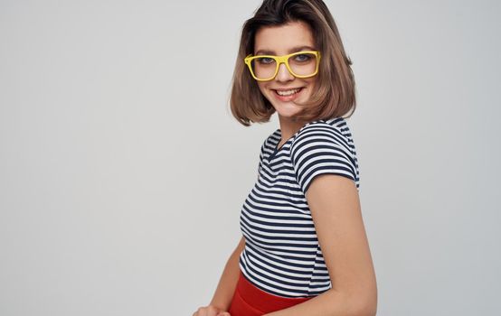 fashionable woman in glasses and in a striped t-shirt on a light background red skirt. High quality photo