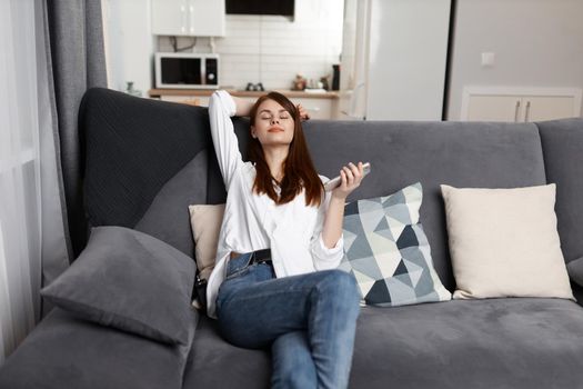 woman with closed eyes Resting at home on a comfortable sofa with a phone in her hands. High quality photo