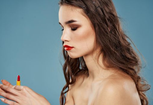 Red lipstick on blue background and brunette model female hands cropped view. High quality photo