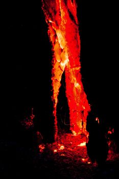An eerie image of a smouldering tree trunk photographed at night