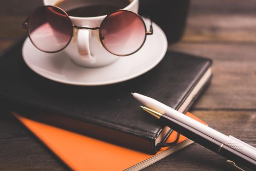 glasses notepads the office handle a cup of coffee saucer wooden table. High quality photo