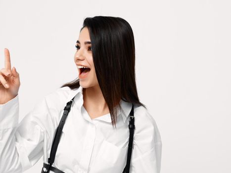 pretty brunette in a white shirt gesturing with her hands on a light background. High quality photo